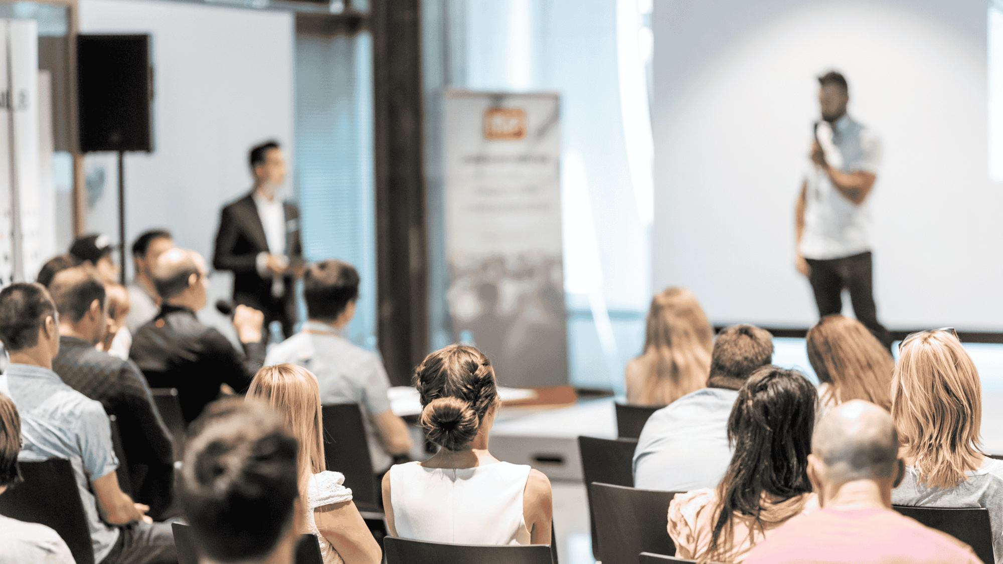 Mies puhuu mikrofoniin lavalla